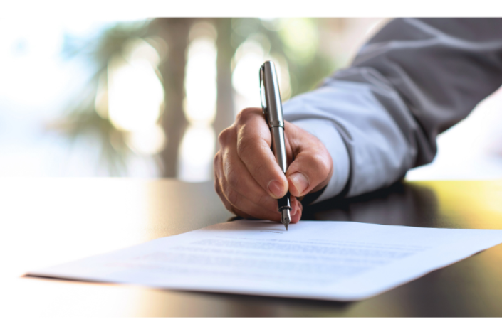 someone holding a pen to sign a document. only the hand and arm of the person is visible.