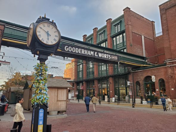 view of distillery district - red brick buildings in the background and a clock in the foreground with flowers on it