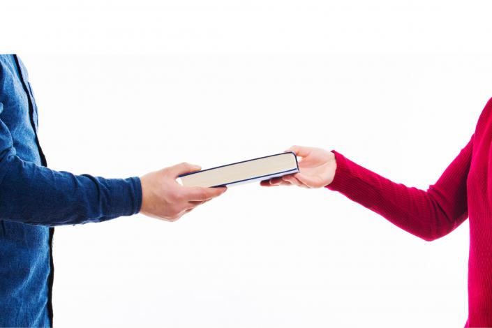 person handing book to another person