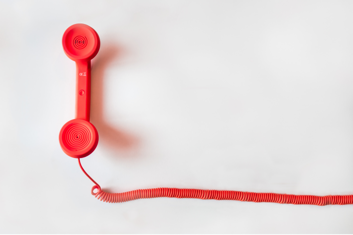 red phone handset on a white background. the cord connected to the phone leads out of frame