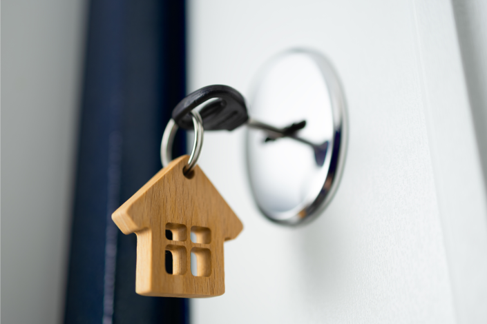 key in a door lock. a wooden house hangs from the key ring